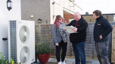 G1 installer talking to customer stood next to Grant UK heat pump